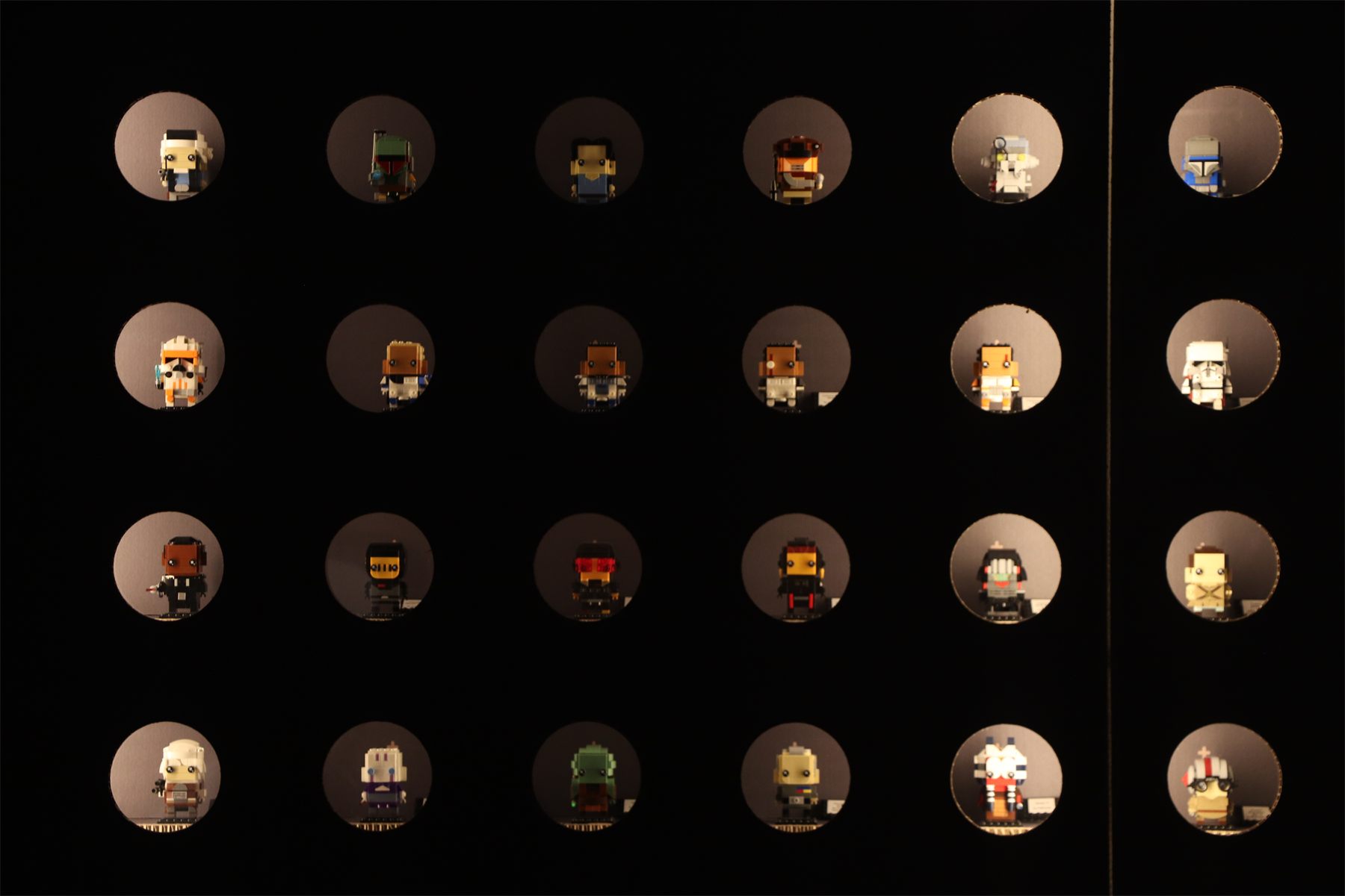 A dark wall of small lit niches, each holding a single minifigure