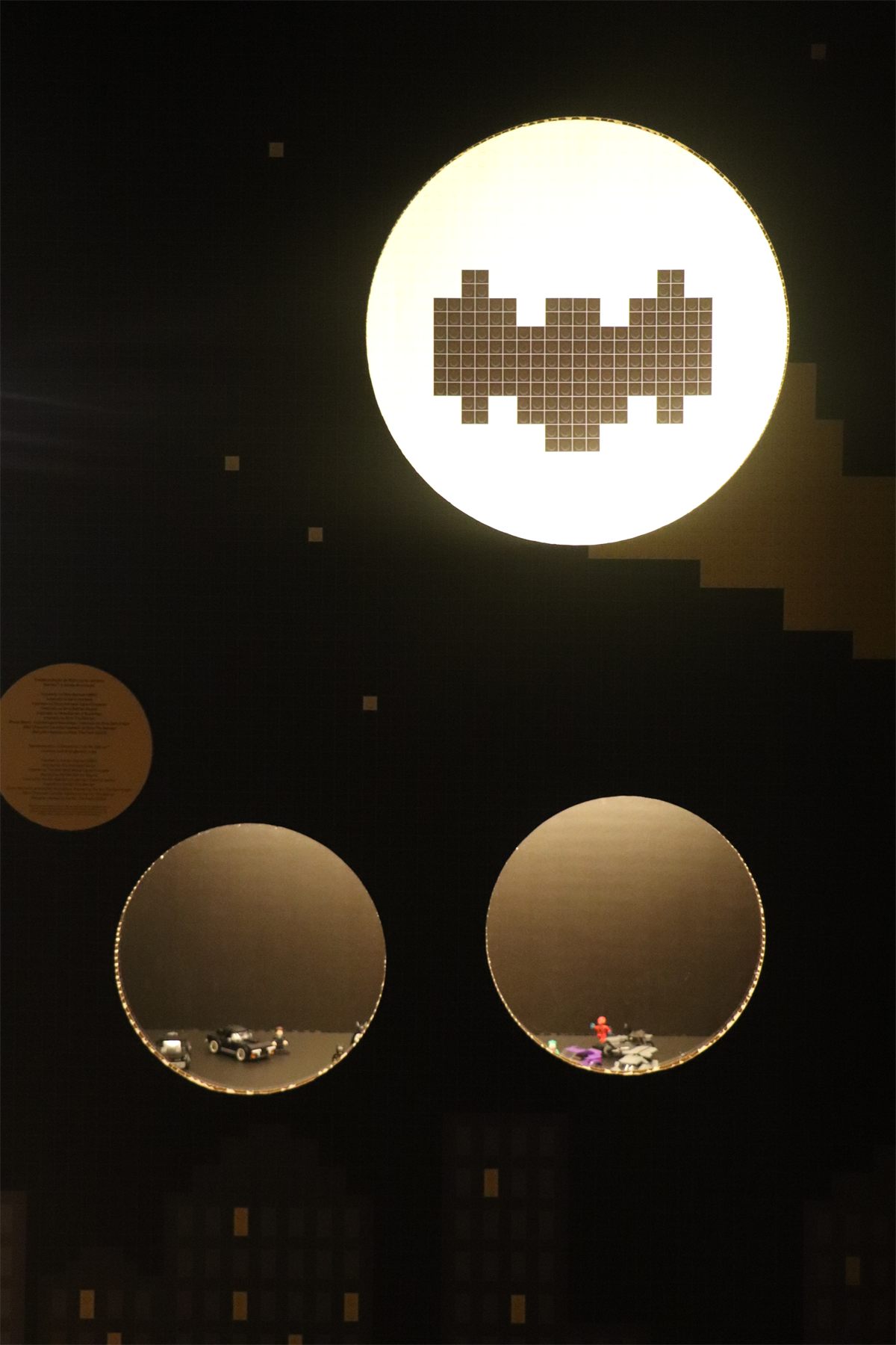 A dark room with large lit discs on the wall, one carrying a pixel figure