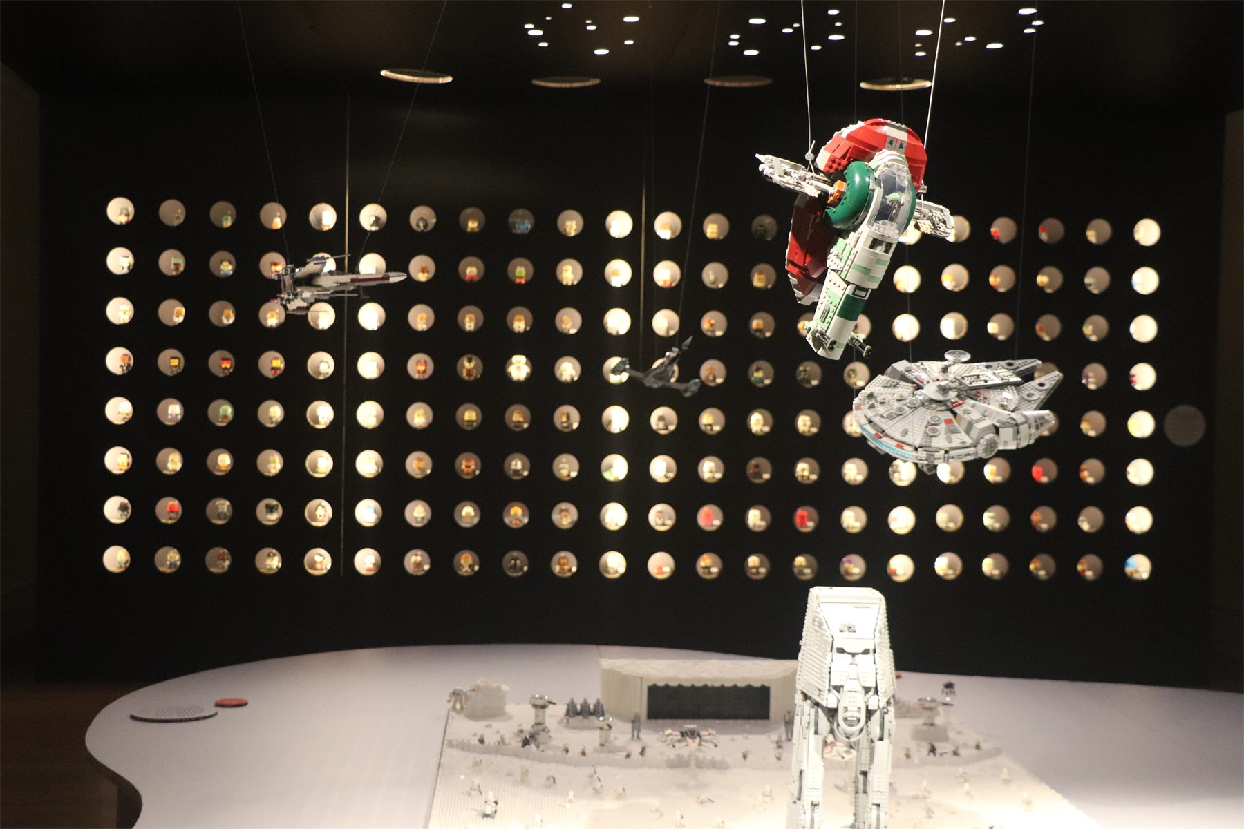 Brick World: a wall of lit niches holding minifigures, with LEGO spacecraft suspended above the diorama