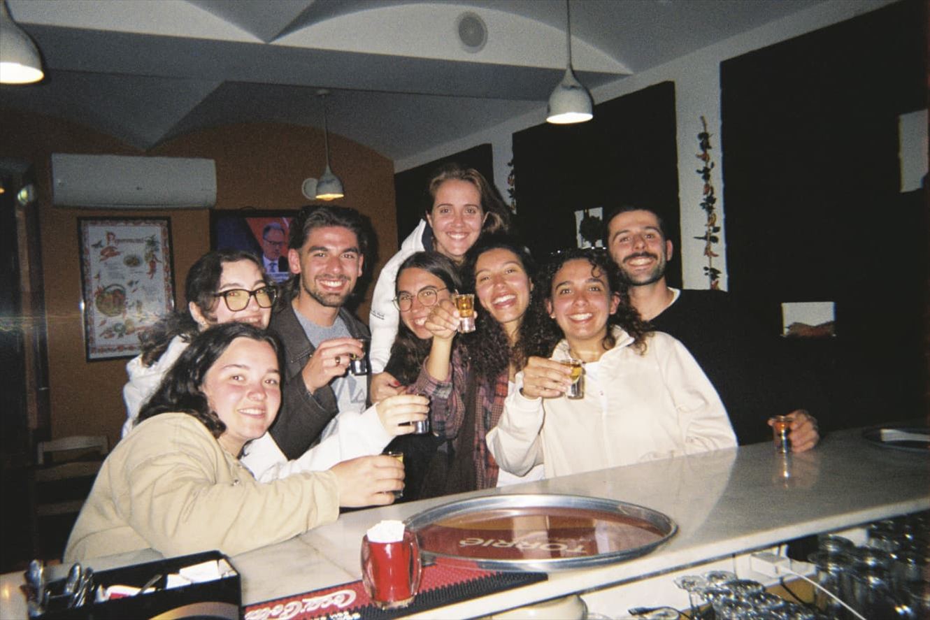 A crowd of friends at a bar counter, glasses raised together