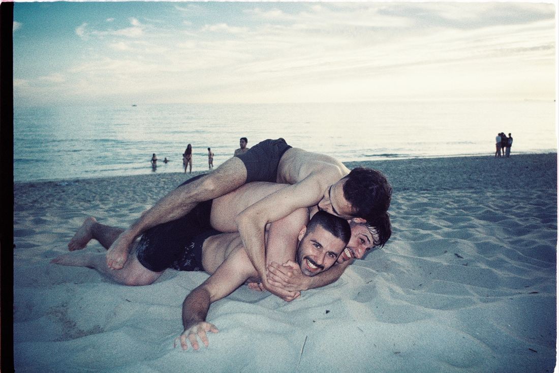 Friends wrestling in the sand on a beach