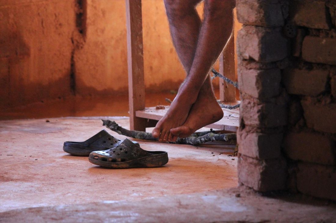 Feet working the treadle of a potter&rsquo;s wheel on a brick floor