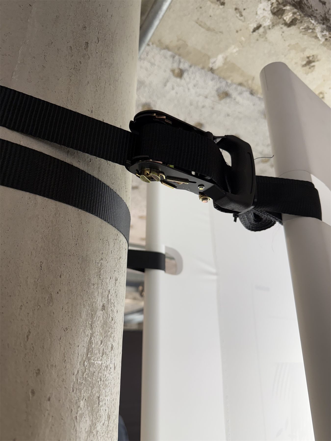 Ratchet straps holding the steel tube against a concrete column