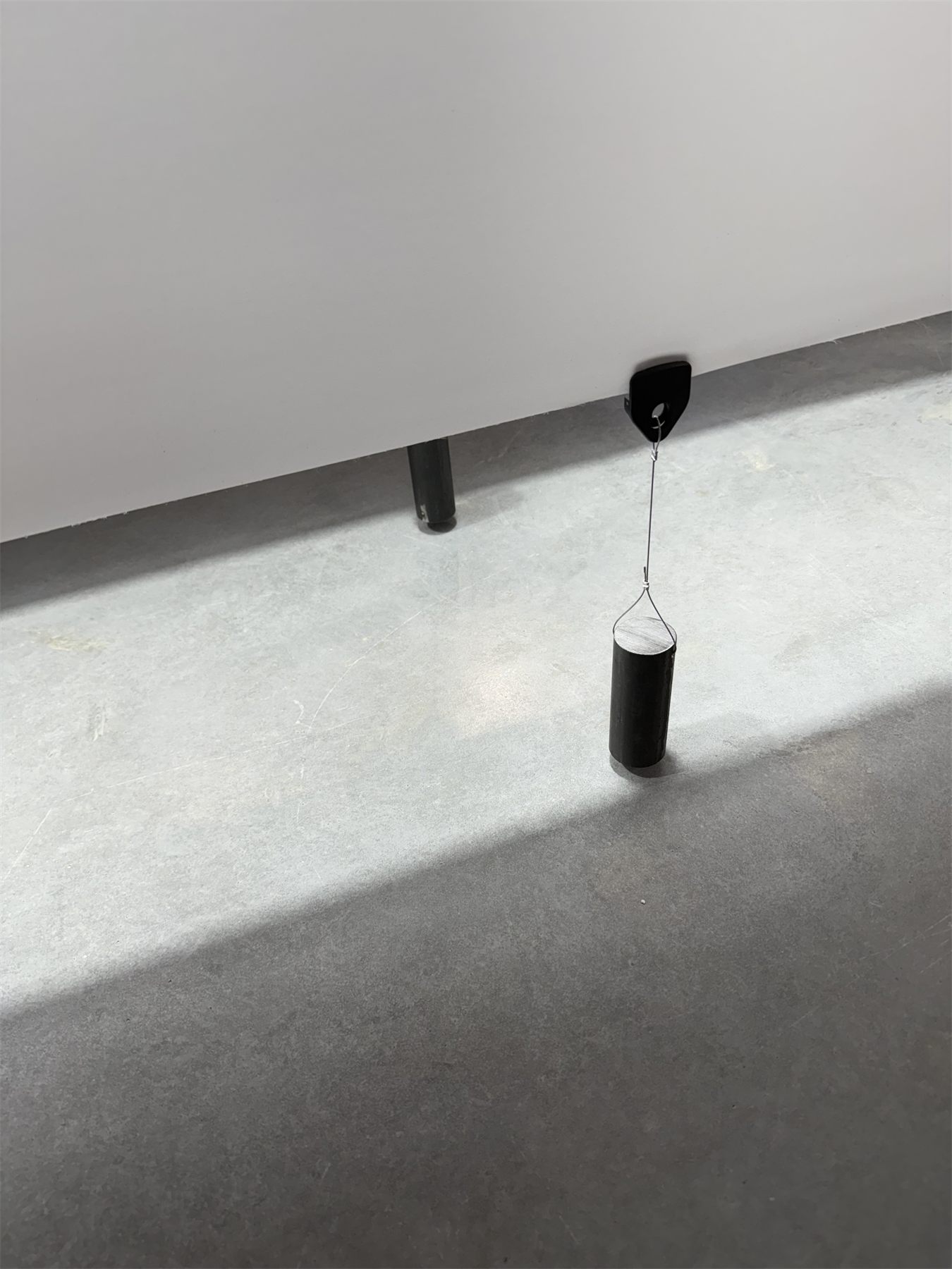 A weight hanging from a clip at the edge of a fabric panel, adding tension