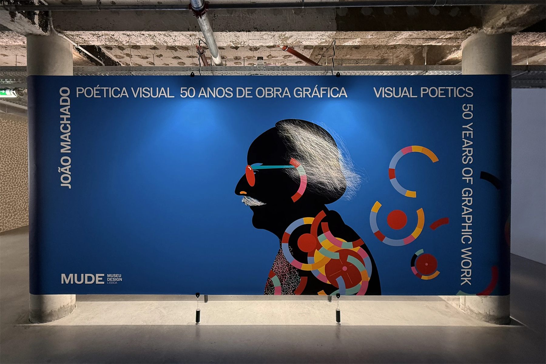MUDE: the exhibition's blue title wall, João Machado's portrait across it in cut colour