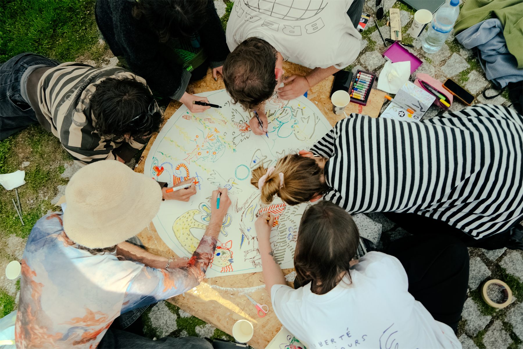 Seen from above: a group lying around one large circular sheet, all drawing on it together